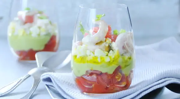 Verrine avocat crevette : couches de tomates, avocat crémeux, œuf dur et crevettes roses, garnie de coriandre. Un délice frais.