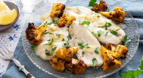 Délicieux poisson aiglefin poêlé, servi avec du chou-fleur rôti et garni de persil frais.