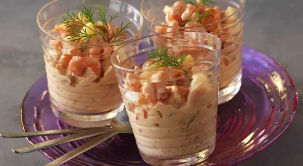 Trois verrines garnies de crevettes et d'une onctueuse sauce cocktail, décorées d'aneth.