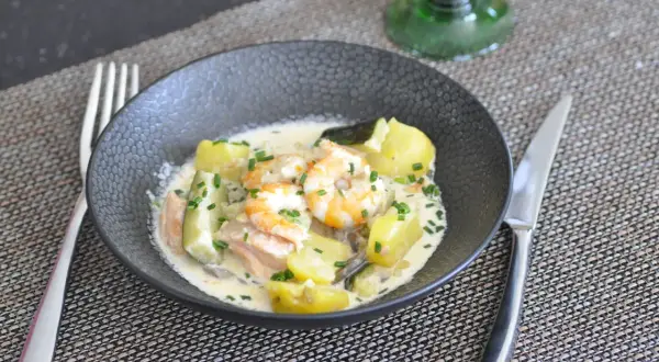 Un savoureux navarin de la mer avec crevettes, saumon, pommes de terre et courgettes, nappé d'une sauce crémeuse et garni de ciboulette.