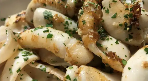 Délicieuse seiche à la plancha, dorée et parsemée de persil frais. Un plat simple et savoureux.
