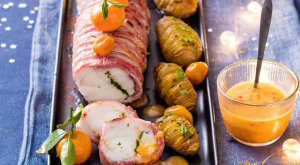Lotte enroulée de lard, servie avec des pommes de terre Hasselback et une sauce pour lotte au lard onctueuse.