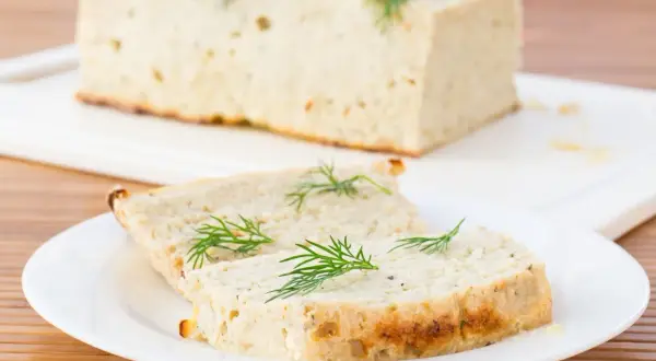 Tranche de terrine de poisson maison, garnie d'aneth frais, prête à être dégustée.