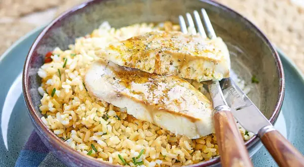Deux filets de poisson blanc, assaisonnés et servis sur un lit de riz. Le lieu noir est-il un bon poisson ? Oui, il est délicieux ainsi !