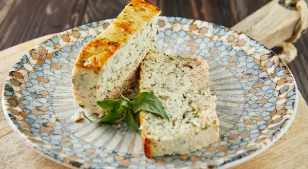 Deux tranches de pains de poisson, garnies d'herbes, sur une assiette décorée.