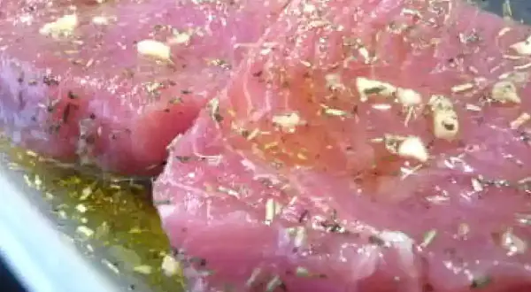 Deux beaux steaks de thon poisson marinés avec de l'ail et des herbes dans une huile dorée.
