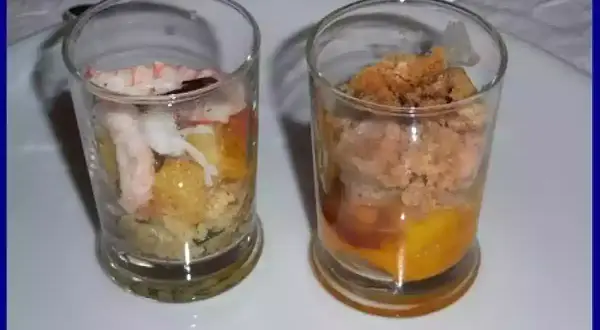Deux verrines garnies : une avec langoustine et légumes, l'autre avec une préparation dorée et crumble.