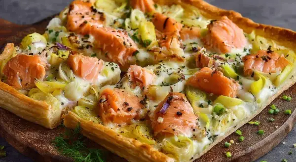 Une délicieuse quiche saumon poireaux, garnie de morceaux de saumon rose et de poireaux tendres sur une pâte dorée.