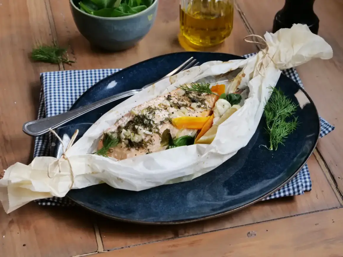 Poisson au four, savoureux et parfumé, enveloppé dans du papier sulfurisé avec des légumes et des herbes fraîches.