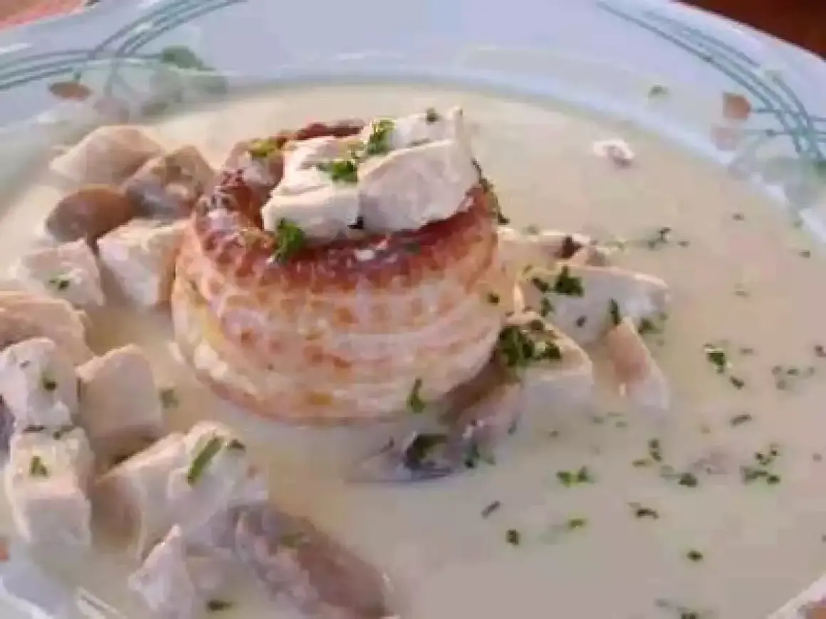 Un délicieux vol au vent aux crevettes, garni de morceaux de volaille et de persil frais, baignant dans une sauce crémeuse.