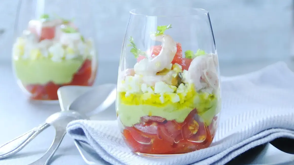 Verrine avocat crevette : couches de tomates, avocat crémeux, œuf dur et crevettes roses, garnie de coriandre. Un délice frais.