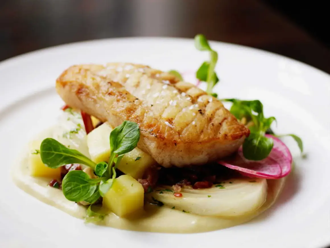 Filet d'églefin recette simple : poisson doré sur lit de purée, pommes de terre cubes, radis et jeunes pousses.