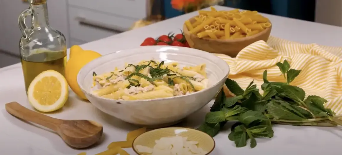 Un plat de pâtes au thon crémeuses, garni de menthe fraîche et de zeste de citron, prêt à être dégusté.