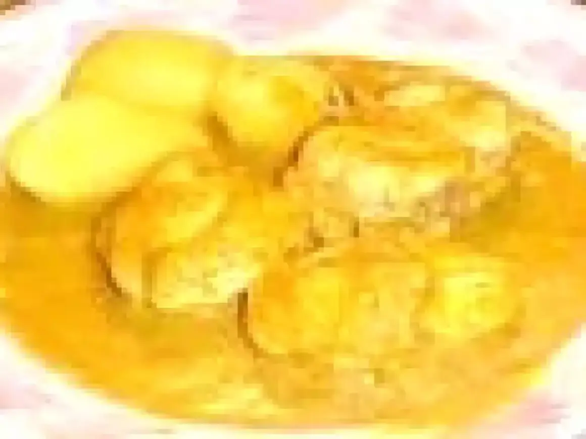 Un plat de bourride de lotte, avec des morceaux de poisson dans une sauce dorée et des pommes de terre.