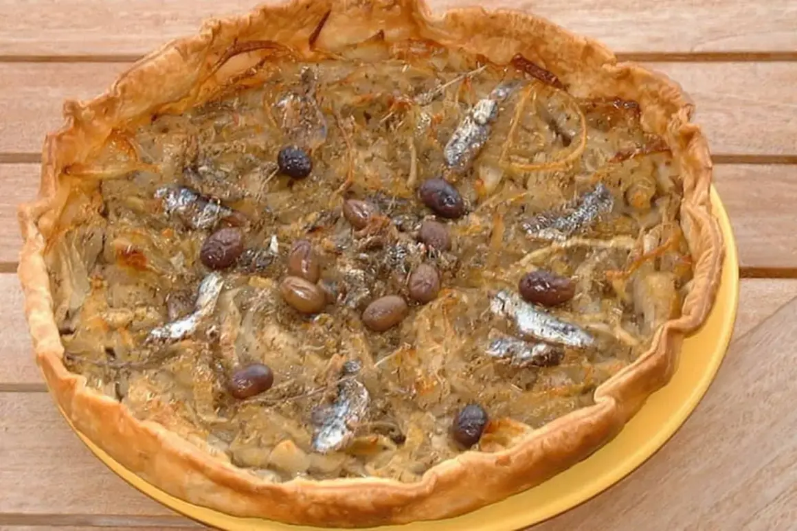 Pissaladière garnie d'anchois et d'olives, sur une pâte brisée ou feuilletée dorée.