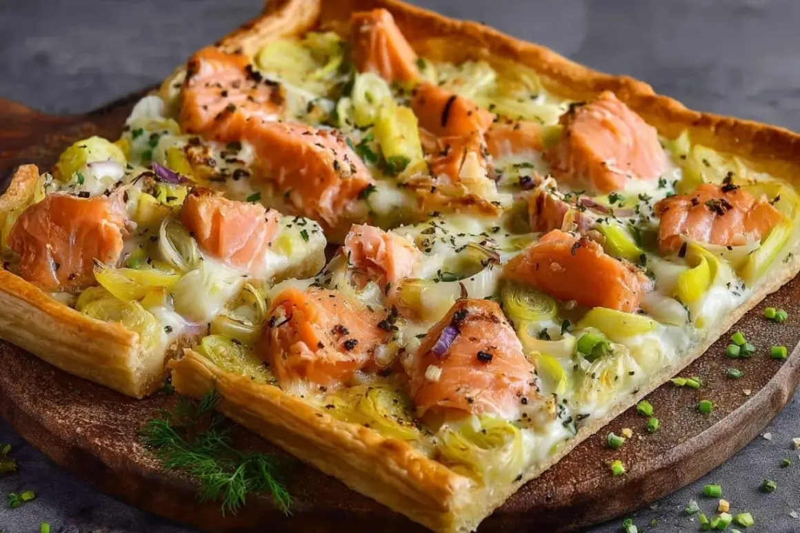 Une délicieuse quiche saumon poireaux, garnie de morceaux de saumon rose et de poireaux tendres sur une pâte dorée.