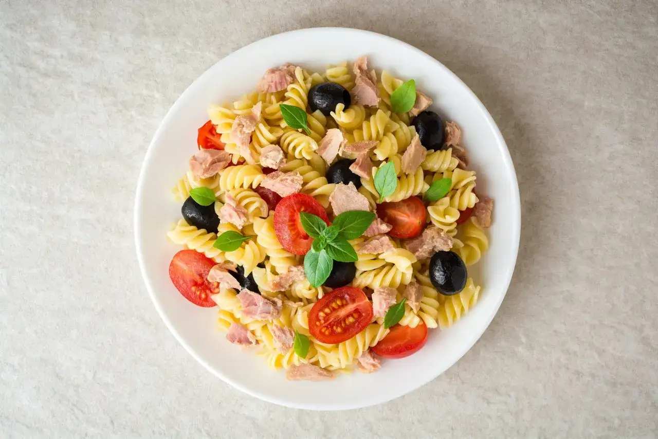 Salade de p&acirc;tes fusilli avec thon &eacute;miett&eacute;, tomates cerises coup&eacute;es, olives noires et feuilles de basilic frais. Un plat simple et savoureux.