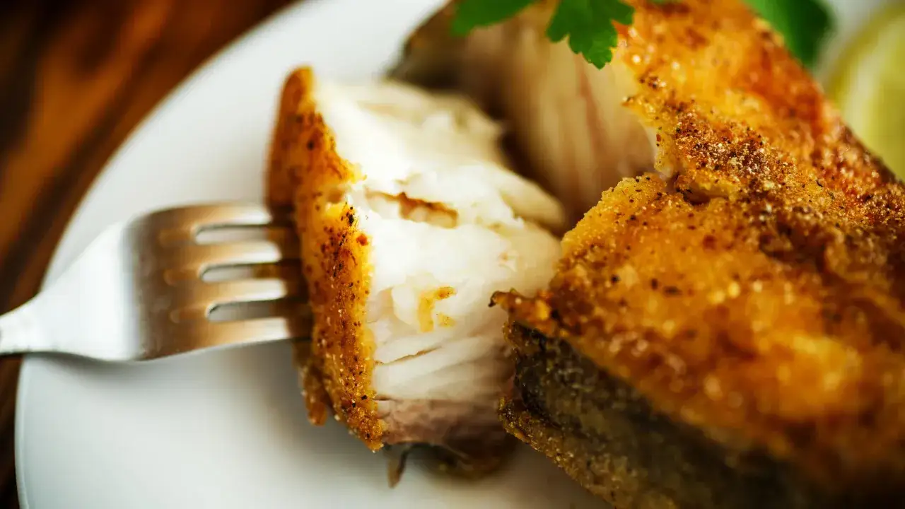 Un morceau de poisson pané, prêt à être dégusté avec une fourchette. Un classique du fish and chips.