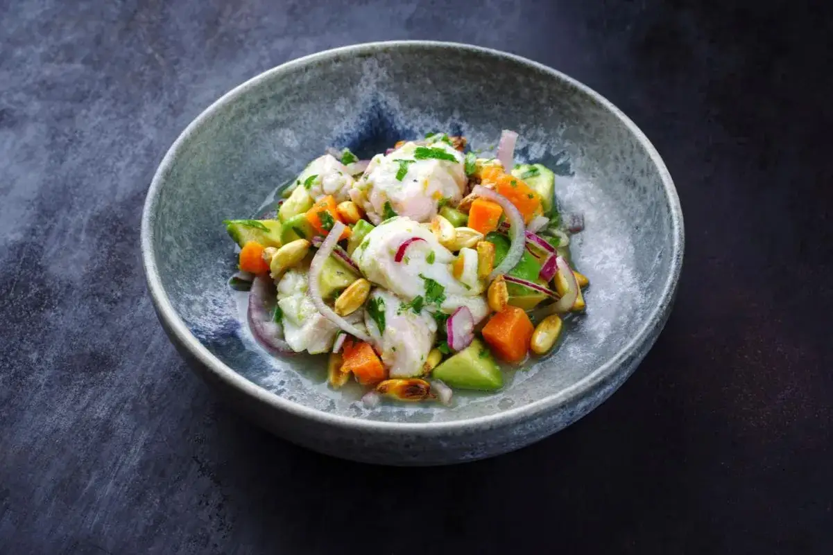 Un plat de ceviche color&eacute; avec du poisson blanc, de l'avocat, des carottes, des oignons rouges et des cacahu&egrave;tes. Une recette ceviche fra&icirc;che et savoureuse.