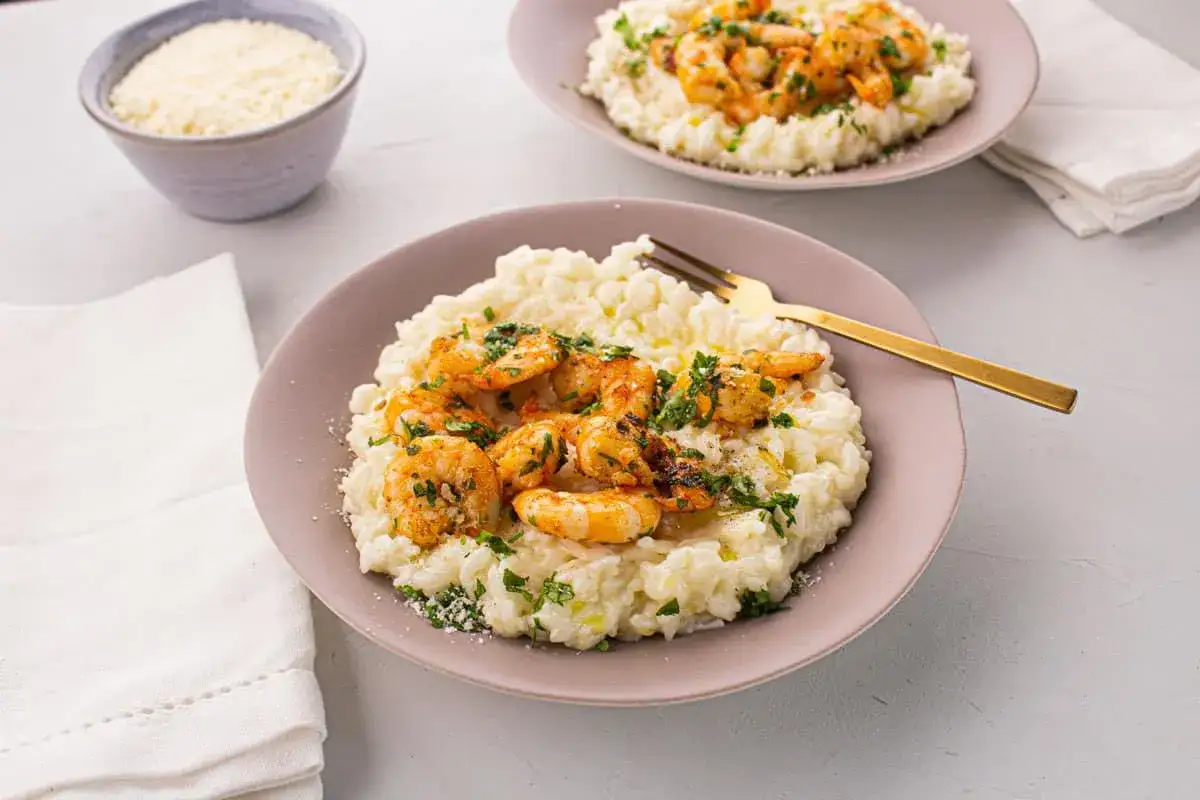 Un crémeux risotto gambas, garni de crevettes poêlées et persil frais, prêt à être dégusté.