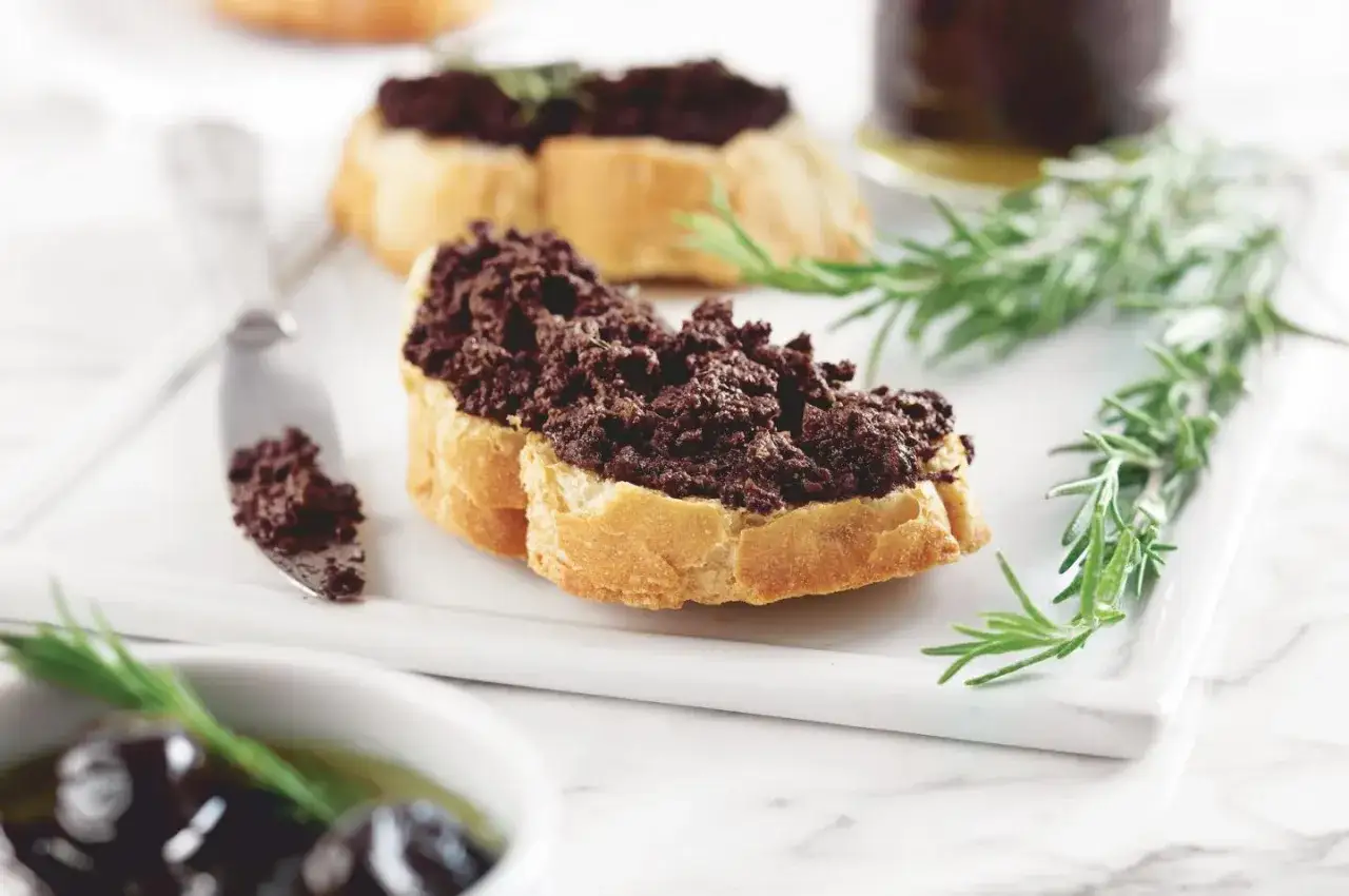 Tranches de pain garnies d'une g&eacute;n&eacute;reuse tapenade de la mer, accompagn&eacute;es de romarin frais.