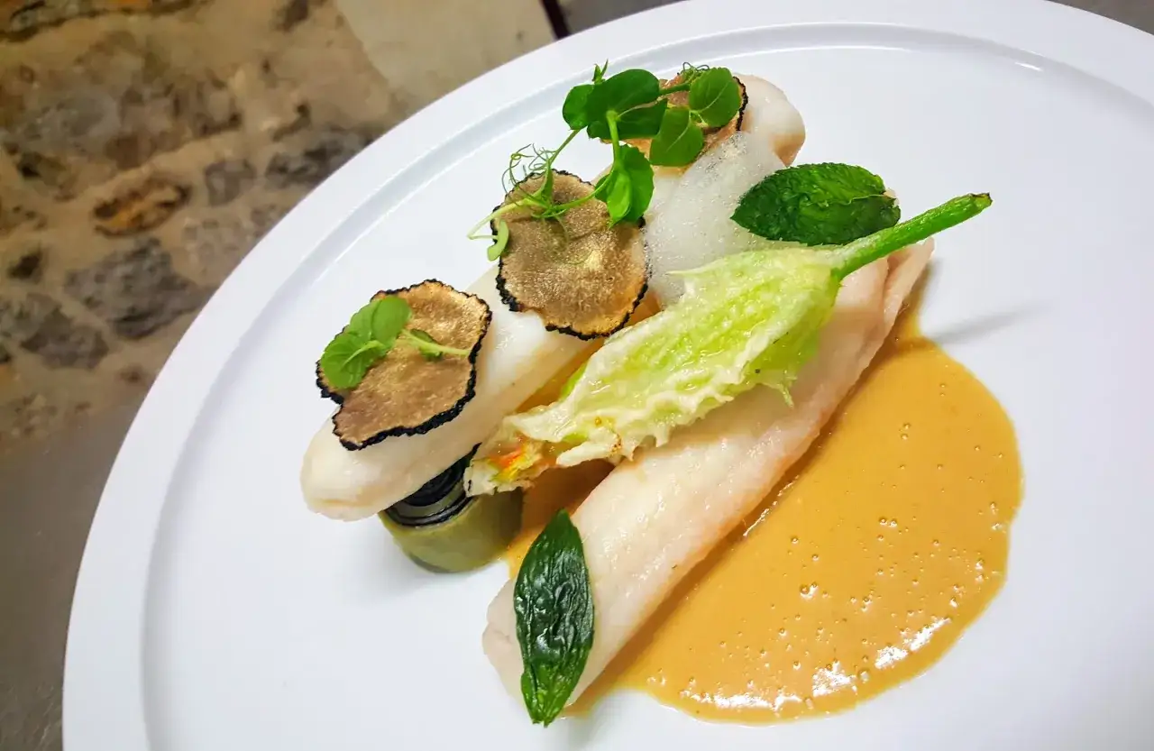 Poisson blanc d&eacute;licat, truffes noires et fleur de courgette en tempura, napp&eacute; d'une sauce onctueuse au beurre nantais.