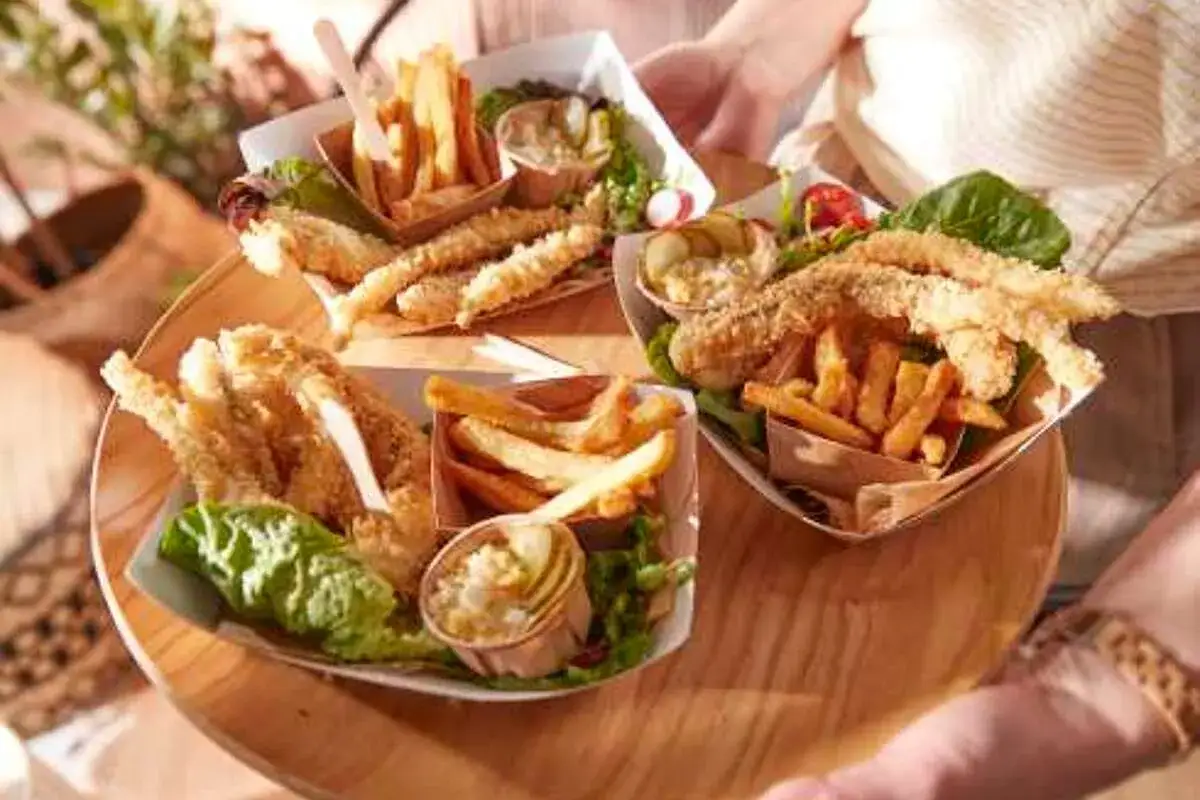 Trois portions de poisson pan&eacute; et frites, accompagn&eacute;es de salade et de sauce tartare.