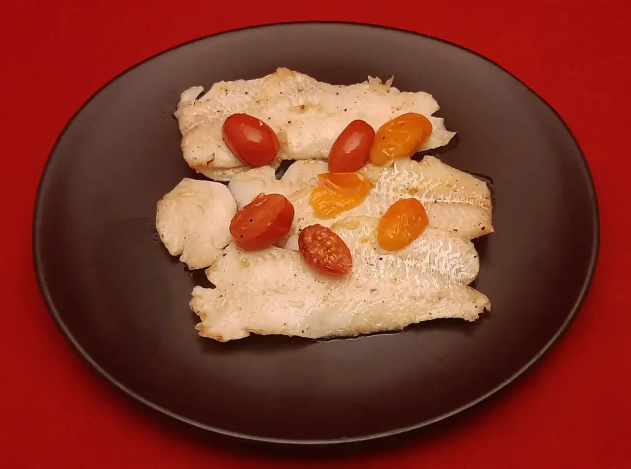 Filets de merlan po&ecirc;l&eacute;s, orn&eacute;s de tomates cerises rouges et jaunes. Une recette simple et savoureuse.