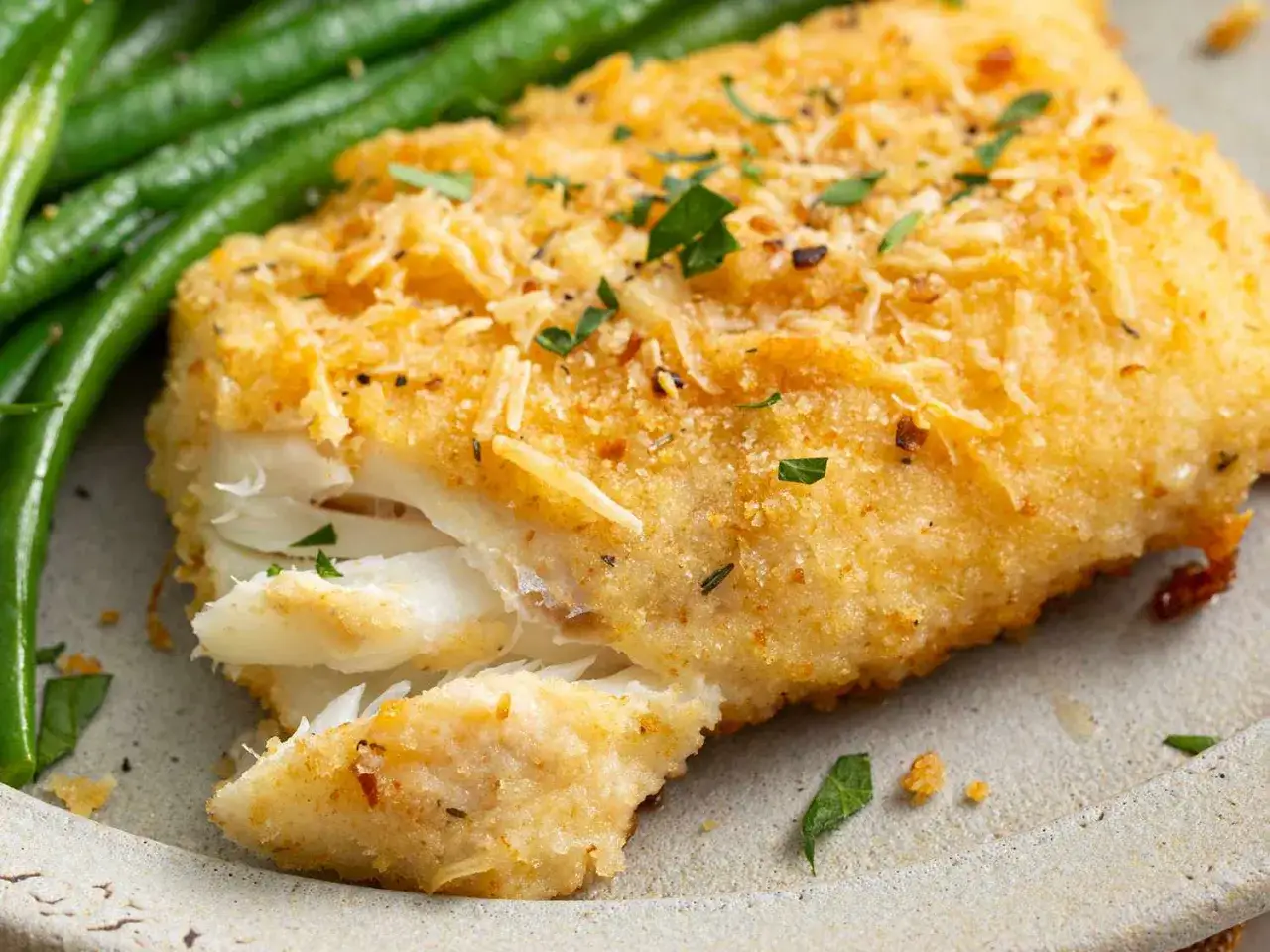 Un d&eacute;licieux filet d'aiglefin pan&eacute;, pr&ecirc;t pour la cuisson, accompagn&eacute; de haricots verts frais.