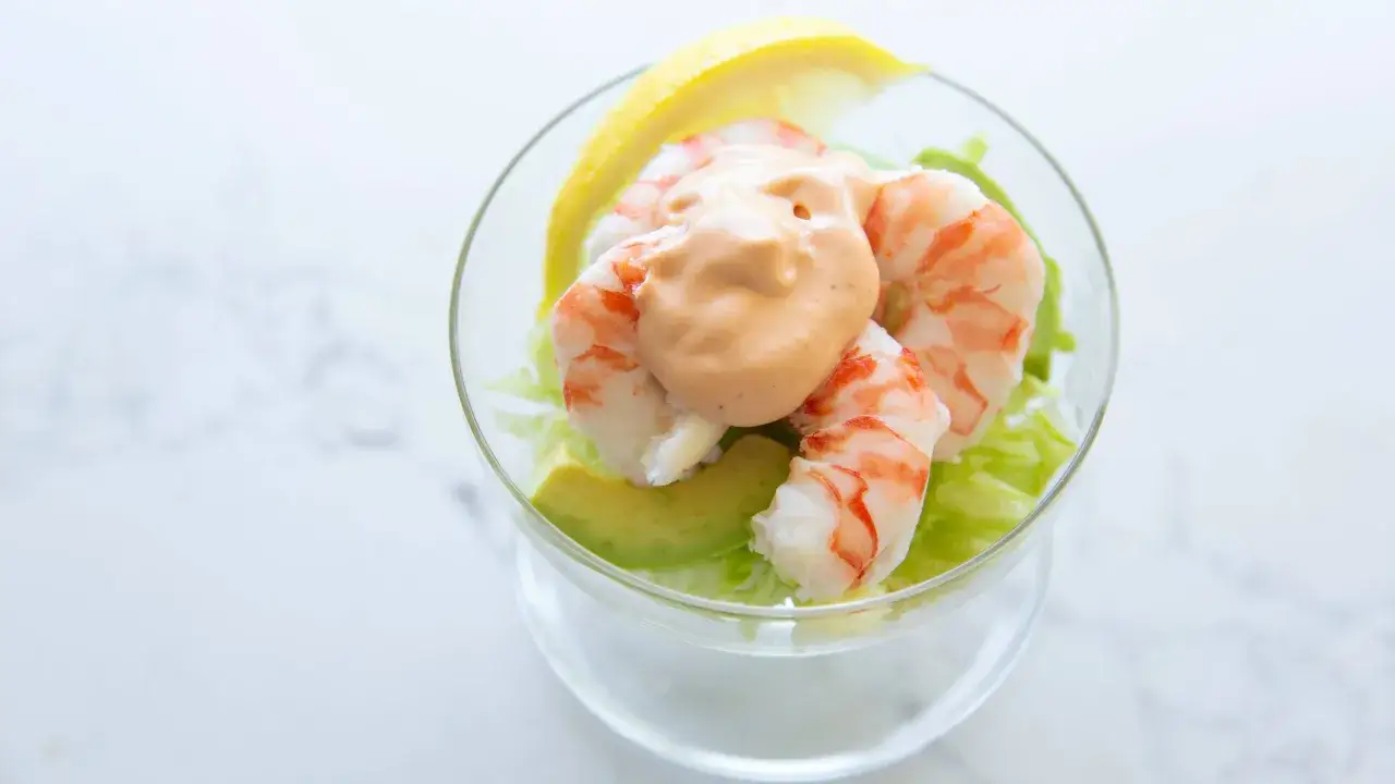 Crevettes roses sur lit de laitue et avocat, napp&eacute;es d'une sauce cocktail onctueuse, garnies d'un quartier de citron.