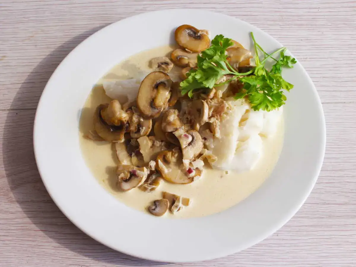 Poisson blanc napp&eacute; d'une onctueuse sauce normande aux champignons, garni de persil frais. Un d&eacute;lice !