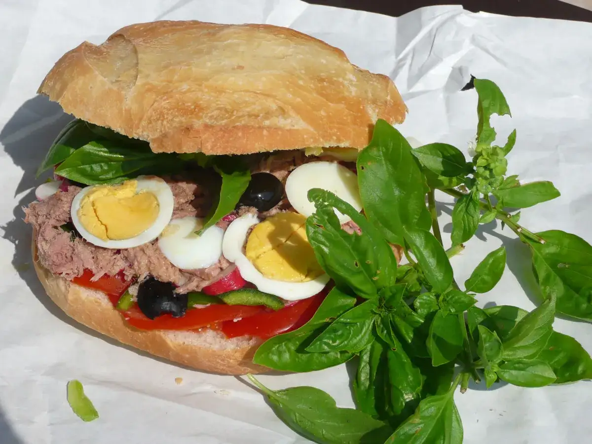 Un g&eacute;n&eacute;reux pan bagnat garni de thon, &oelig;ufs durs, olives, tomates et basilic frais.