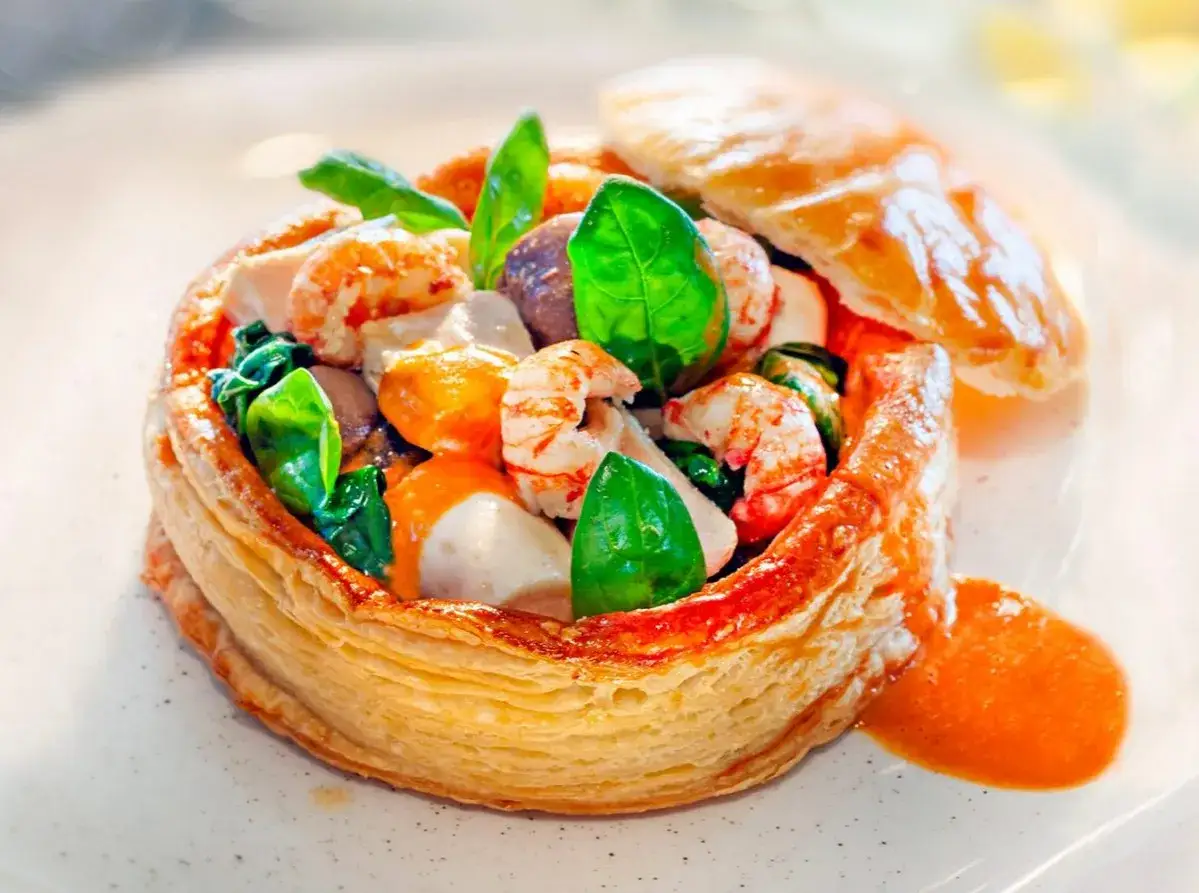 Vol-au-vent garni de fruits de mer et napp&eacute; d'une onctueuse sauce Nantua, d&eacute;cor&eacute; de feuilles de basilic.