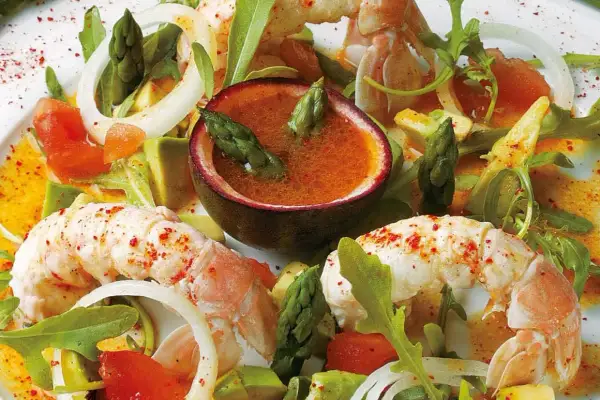 Délicieuse salade langoustine avec asperges, avocat et une sauce fruitée dans une demi-passiflore.