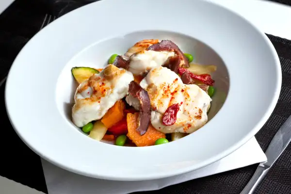 Délicieuse lotte poêlée, servie avec des légumes croquants et des tomates séchées. Un plat savoureux et coloré.