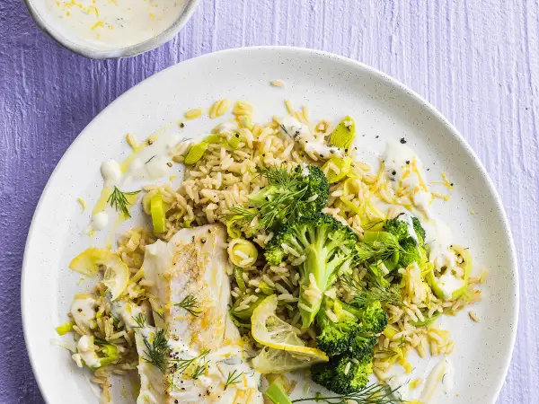 Poisson blanc avec riz, brocolis et poireaux, arrosé d'une sauce aneth crémeuse et garni de citron.