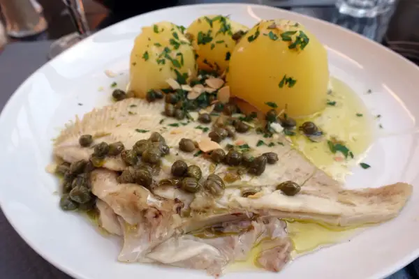 Une aile de raie à la plancha, servie avec des pommes de terre vapeur et une sauce aux câpres et persil. Un plat savoureux et léger.