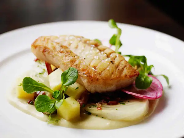 Filet d'églefin recette simple : poisson doré sur lit de purée, pommes de terre cubes, radis et jeunes pousses.