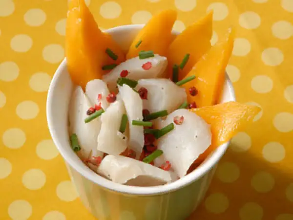 Délicieuse recette cabillaud enfant : morceaux de poisson blanc, mangue fraîche, ciboulette et poivre rose dans un bol.