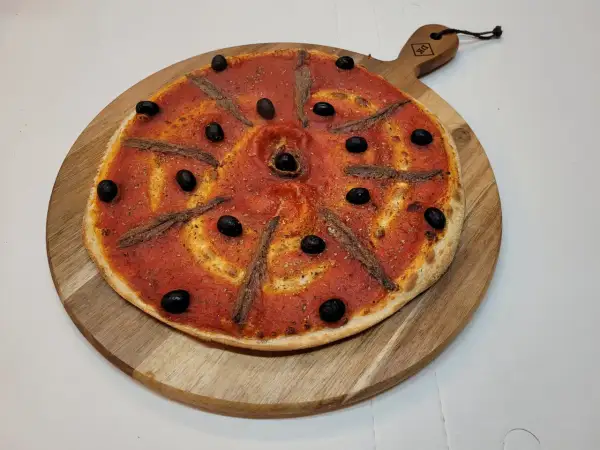 Pizza à la sauce tomate, olives noires et anchois, prête à être dégustée. Une recette simple et savoureuse.