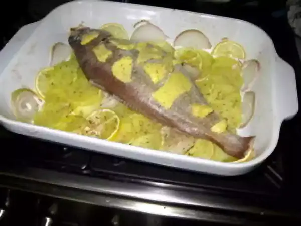 Poisson entier préparé pour la cuisson, avec des rondelles de citron et d'oignon. Une belle tacaud recette en préparation.