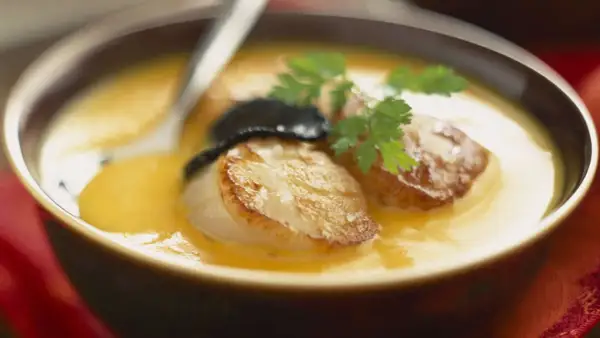 Velouté de butternut avec saint jacques poêlées, garni de persil et d'une touche de truffe.