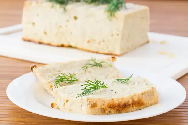 Tranche de terrine de poisson maison, garnie d'aneth frais, prête à être dégustée.