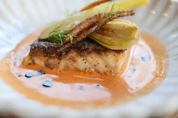 Un filet de poisson poêlé, garni de fenouil et de fines herbes, baignant dans un onctueux fumet de poisson orangé.