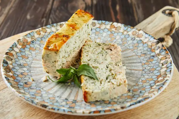 Deux tranches de pains de poisson, garnies d'herbes, sur une assiette décorée.
