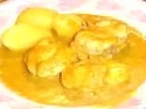Un plat de bourride de lotte, avec des morceaux de poisson dans une sauce dorée et des pommes de terre.